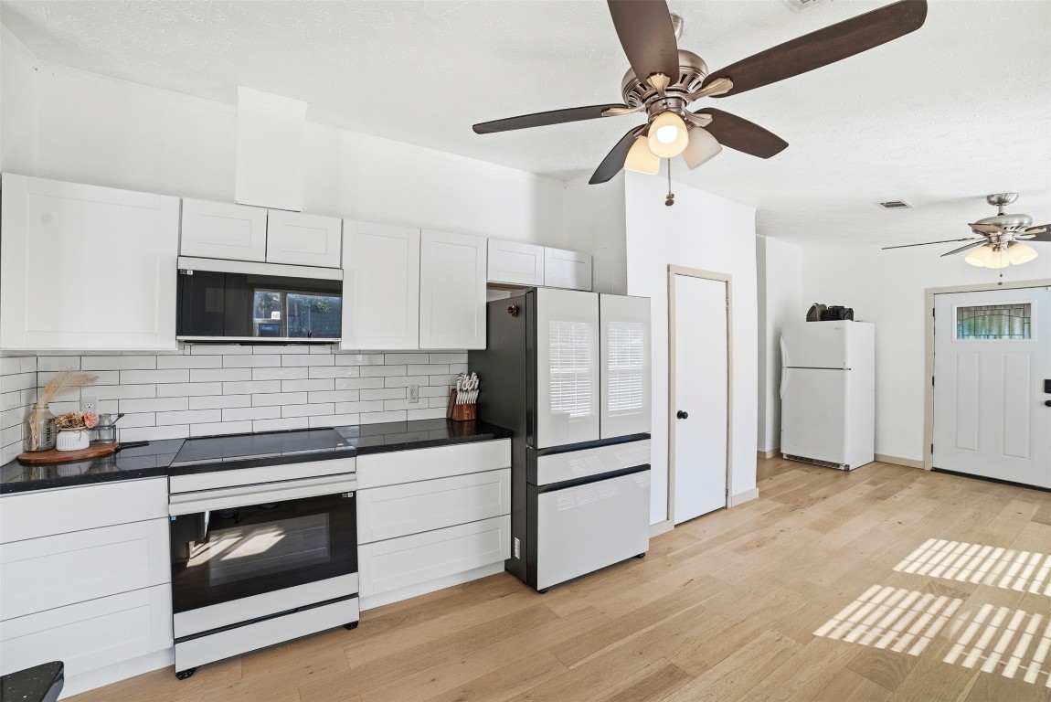 4048 Sutherland Springs Road Seguin, TX 78155 - Photo 9 of 23 a kitchen with granite countertop a refrigerator stove and white cabinets