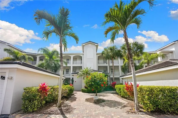 a view of a house with a yard and palm trees