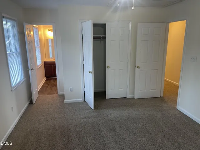 a view of a hallway with wooden floor and a bathroom