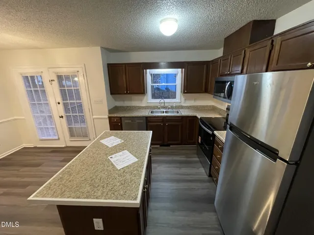 a kitchen with stainless steel appliances granite countertop a refrigerator and a stove