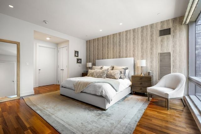 a spacious bedroom with a bed and chair