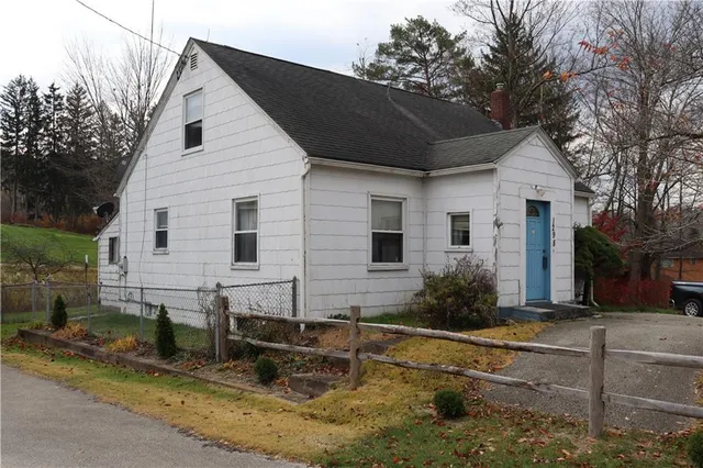 a backyard of a house with potted plants and large tree