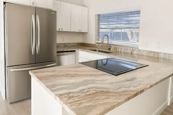 a kitchen with granite countertop a refrigerator and a sink