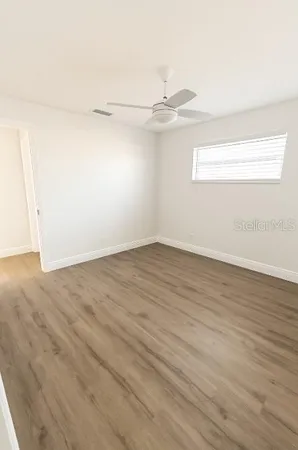an empty room with wooden floor and fan
