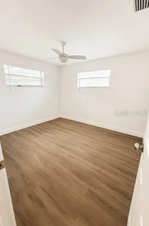 an empty room with wooden floor and windows