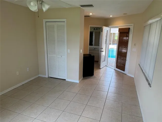 a view of a refrigerator in kitchen and an empty room with windows
