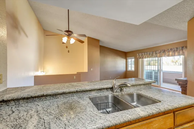 a kitchen with a granite countertop sink and natural light