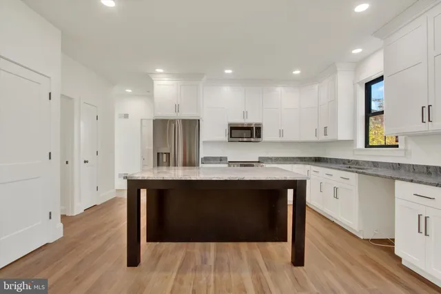 a kitchen with stainless steel appliances granite countertop a white cabinets and wooden floor