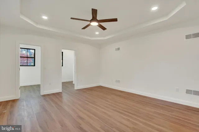 an empty room with wooden floor ceiling fan and windows