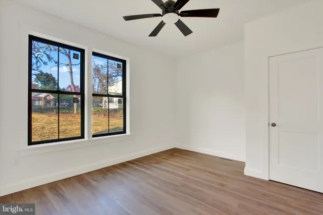 a view of an empty room with window and wooden floor