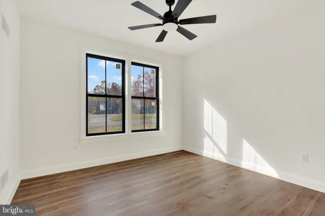 an empty room with wooden floor fan and windows