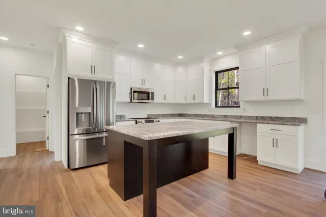 a kitchen with a center island wooden floor and stainless steel appliances