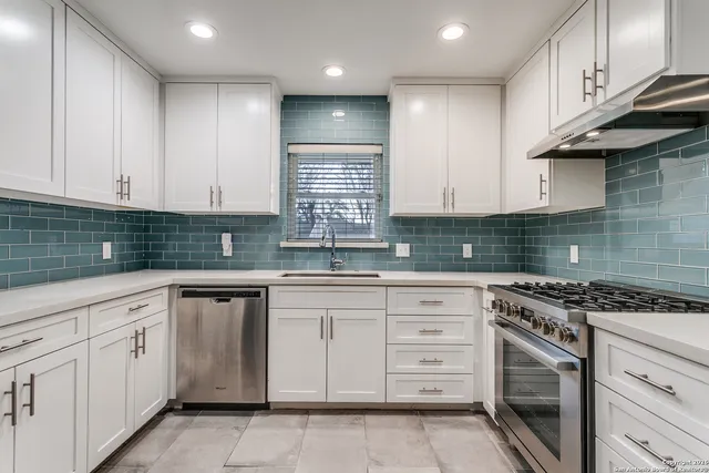 a kitchen with granite countertop white cabinets stainless steel appliances and a sink