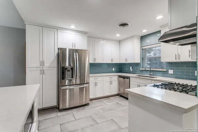 a kitchen with granite countertop a refrigerator and a stove top oven
