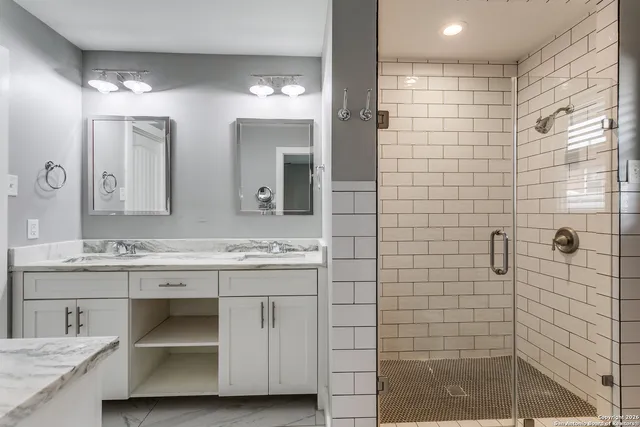 a bathroom with a granite countertop sink a mirror and a shower