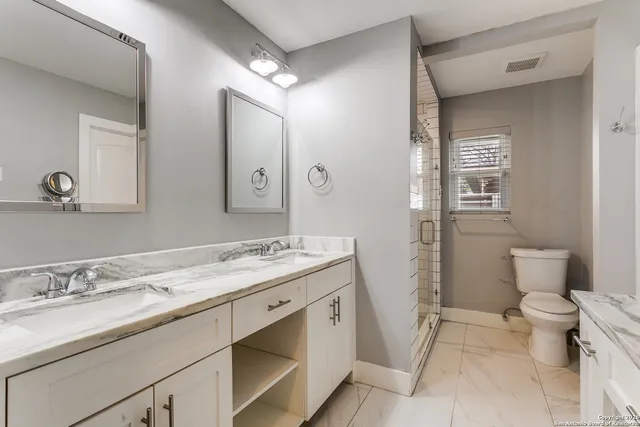 a bathroom with a granite countertop sink a toilet and a mirror