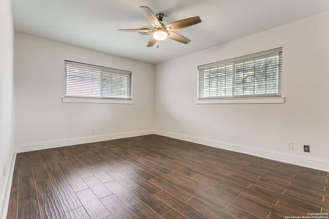 an empty room with wooden floor and windows