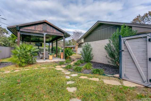 a backyard of a house with table and chairs under an umbrella