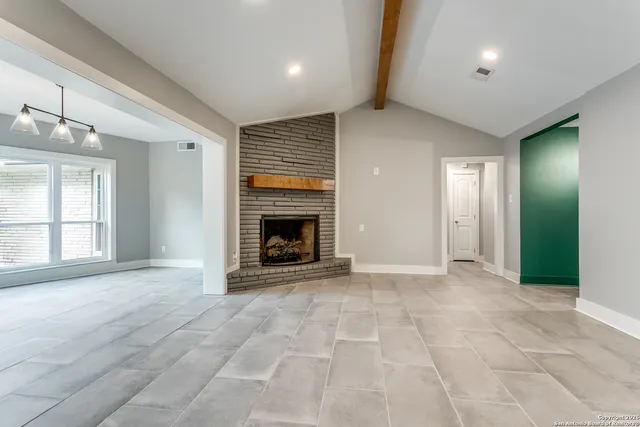 an empty room with windows and fireplace