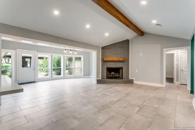 a view of an empty room with a fireplace and a window