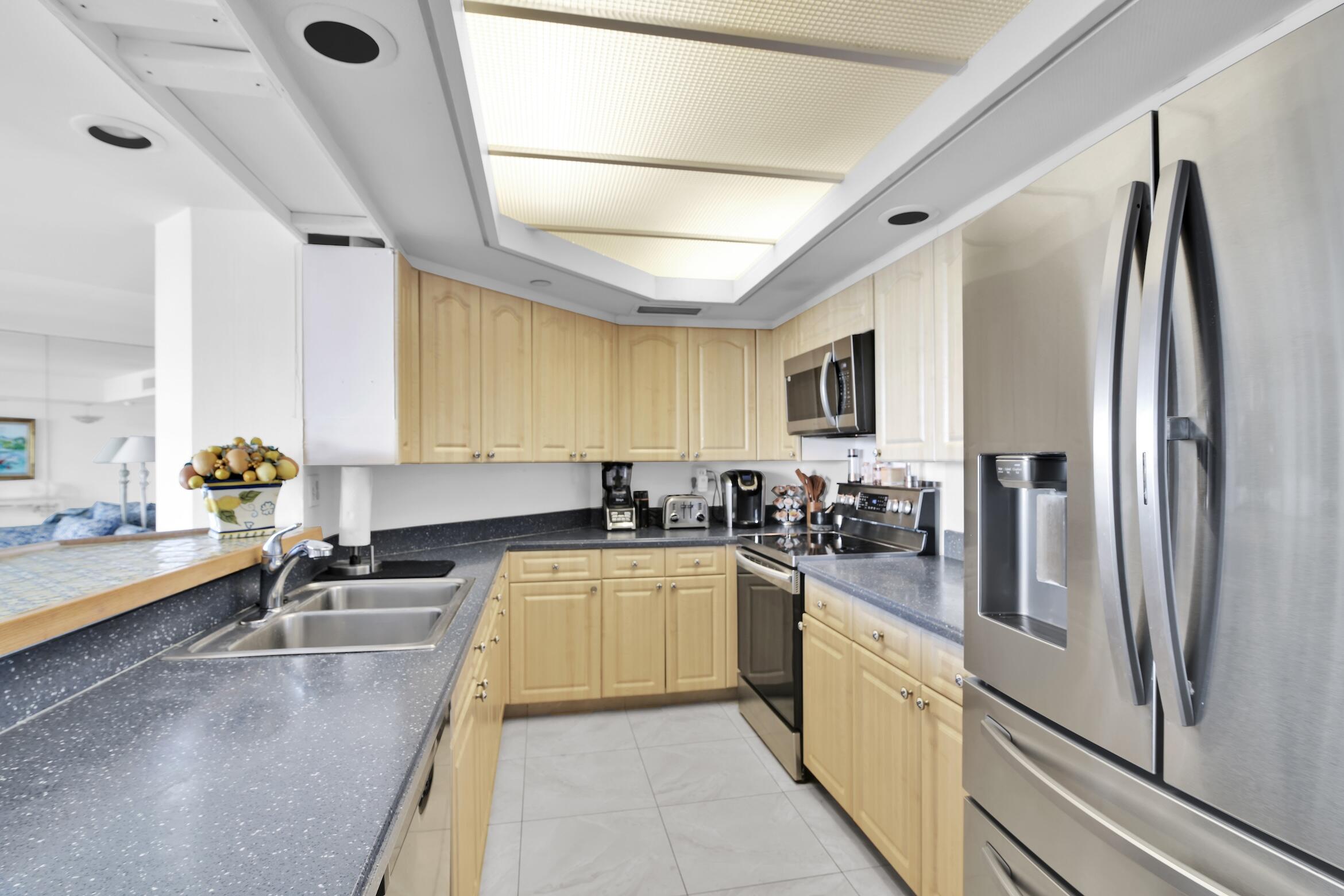 120 Southeast 5th Avenue, Unit 331 Boca Raton, FL 33432 - Photo 10 of 48 a large kitchen with a stove a sink dishwasher a refrigerator and cabinets with wooden floor