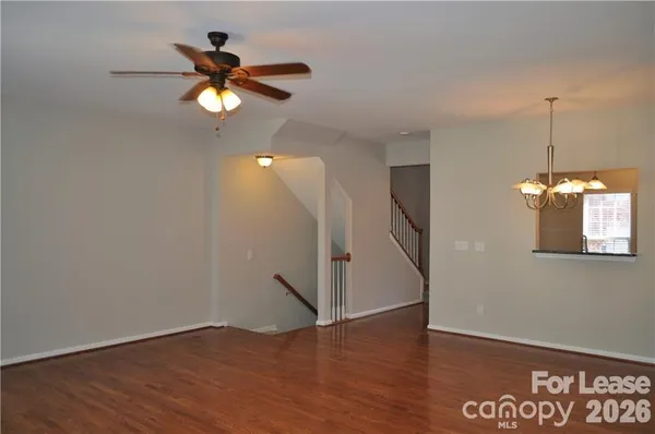 a view of an empty room with wooden floor and a ceiling fan