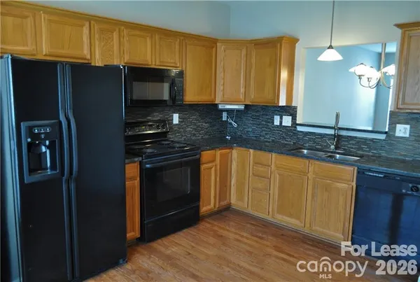 a kitchen with granite countertop wooden cabinets a stove top oven and stainless steel appliances