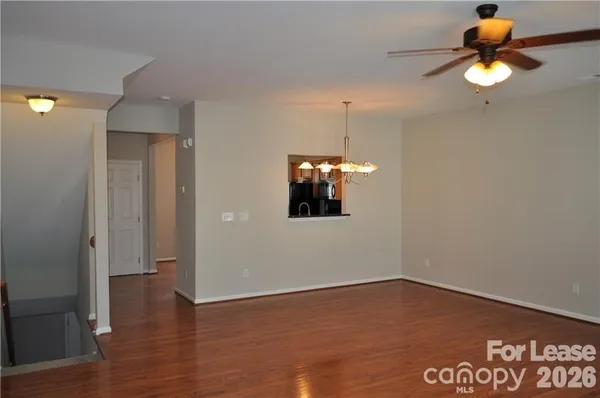 an empty room with wooden floor and chandelier fan