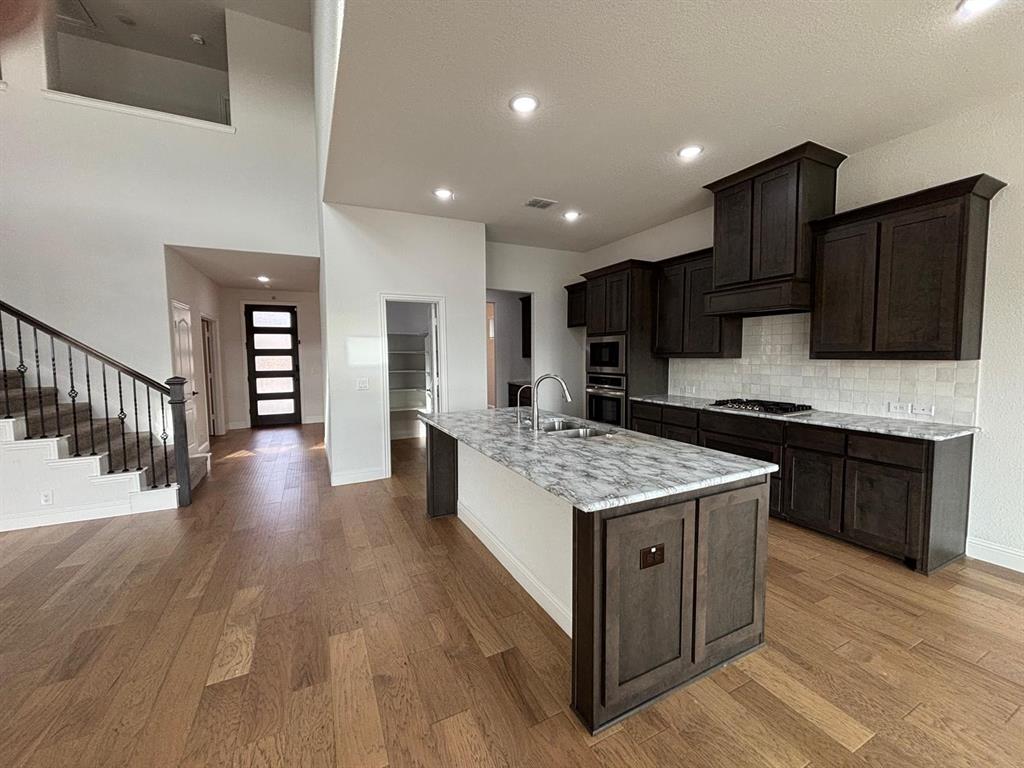 1080 Canuela Way Justin, TX 76247 - Photo 4 of 30 a kitchen with stainless steel appliances granite countertop a stove and a wooden floors