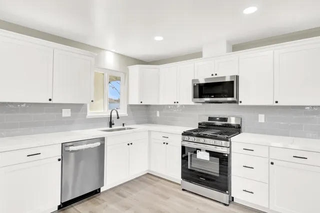 a kitchen with white cabinets sink and stainless steel appliances