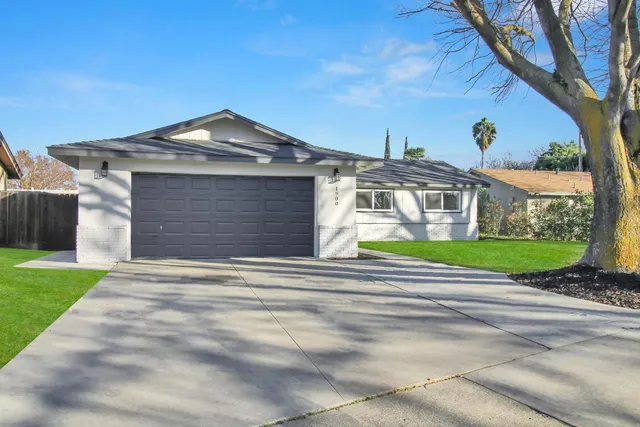 a front view of a house with a garden and trees