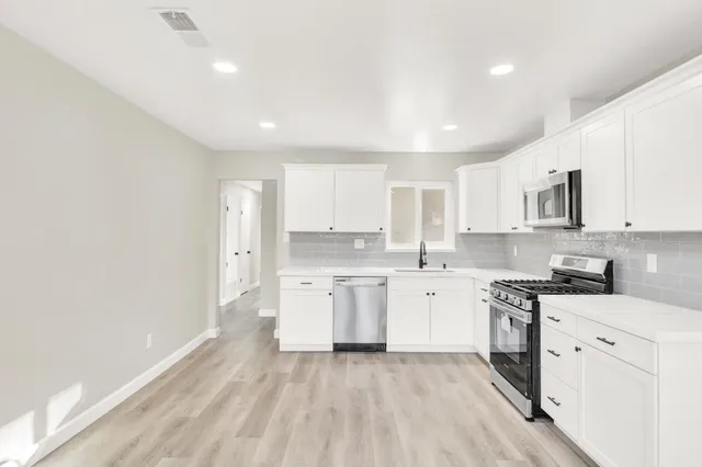 a kitchen with a sink a stove cabinets and wooden floor