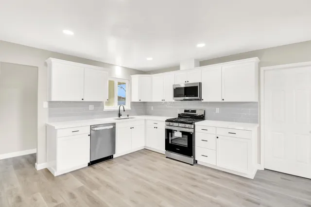 a white kitchen with granite countertop stainless steel appliances