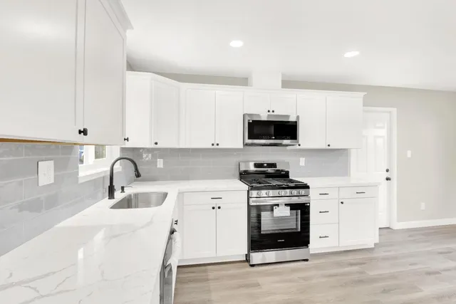 a kitchen with granite countertop a stove a sink and a microwave