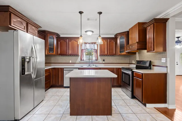 a kitchen with stainless steel appliances granite countertop a refrigerator a sink dishwasher a stove with wooden cabinets