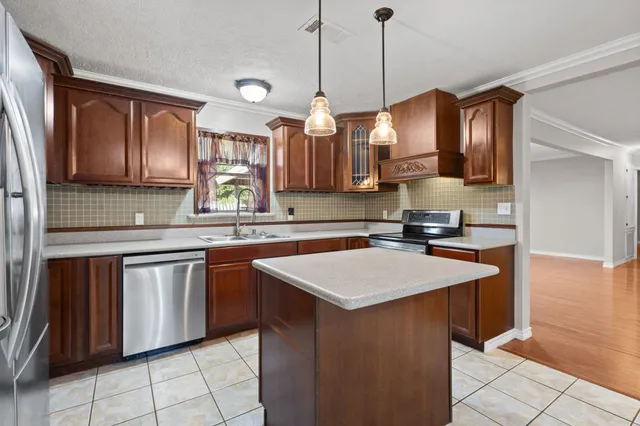 a kitchen with kitchen island granite countertop a sink a stove and a wooden floors