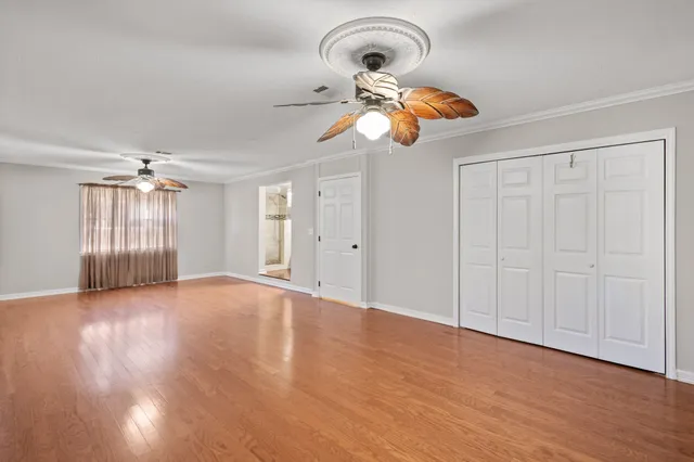 a view of an empty room with window and wooden floor