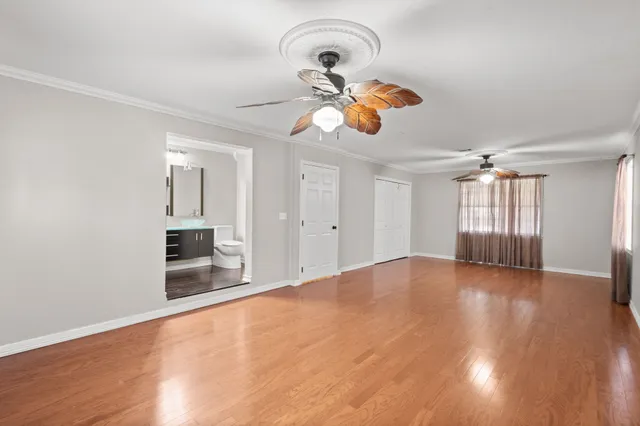 a view of an empty room with a window and wooden floor