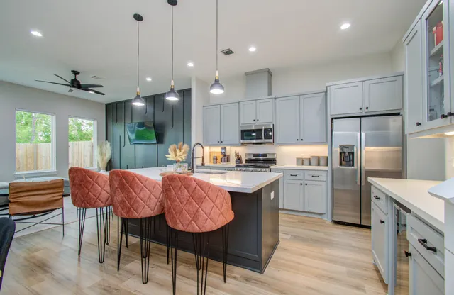 a kitchen with granite countertop a table chairs a sink dishwasher refrigerator and cabinets