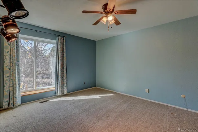 an empty room with windows and ceiling fan