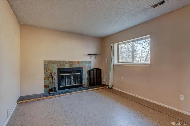 an empty room with windows and fireplace