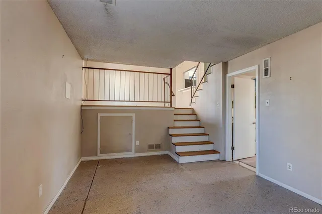 a view of an empty room with stairs and a window