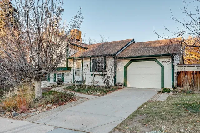 a front view of a house with a garden and trees