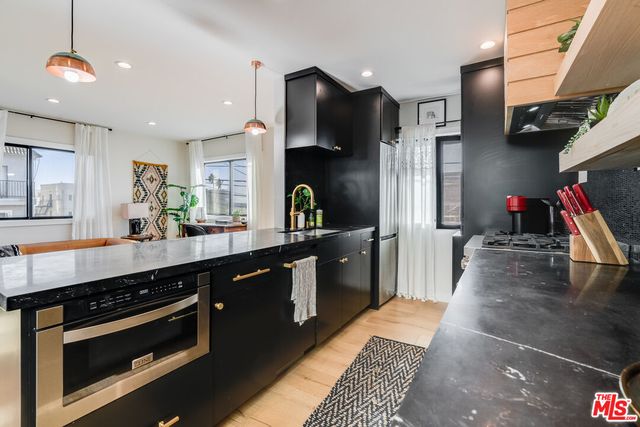 a kitchen with stainless steel appliances kitchen island granite countertop a stove a sink and a refrigerator