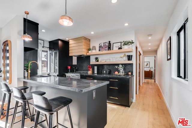 a kitchen with stainless steel appliances granite countertop a stove top oven a refrigerator a sink and a dining table with wooden floor