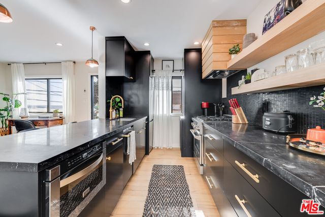 a kitchen with stainless steel appliances granite countertop a sink a stove and a wooden floors