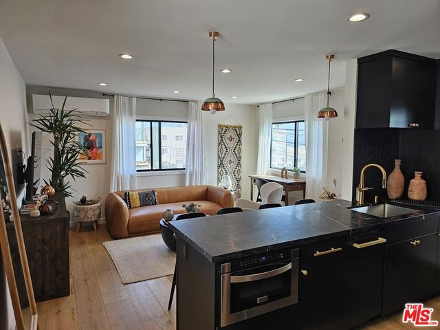 a open kitchen with stainless steel appliances granite countertop a stove a sink dishwasher a dining table and chairs with wooden floor