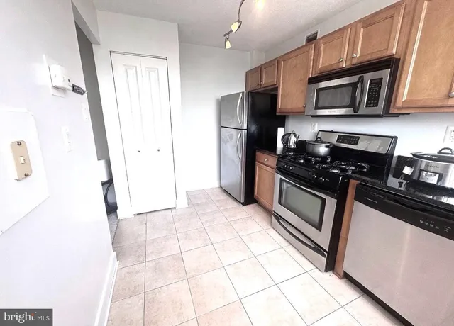 a kitchen with granite countertop a stove a microwave a refrigerator a sink and cabinets