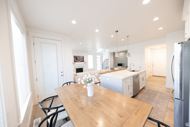 1404 East Rustic Wood Court Sandy, UT 84092 - Photo 6 of 33 Open-concept kitchen and dining area featuring a light-toned wood dining table, white kitchen island with an undermount sink, stainless steel dishwasher, and recessed lighting throughout