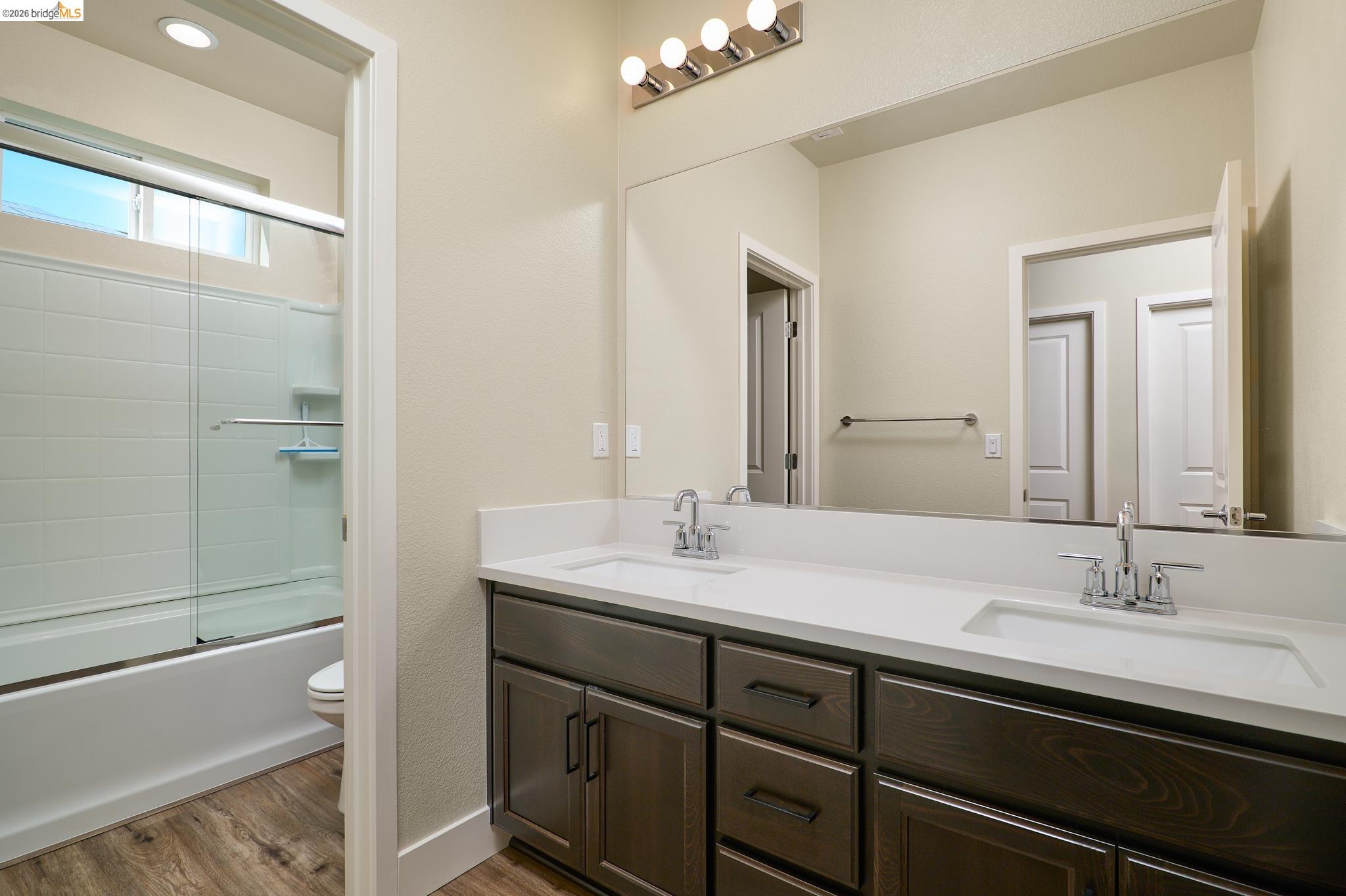 5532 Promontory Way Antioch, CA 94531 - Photo 27 of 45 Full bath featuring double vanity, light wood-style floors, and combined bath / shower with glass door